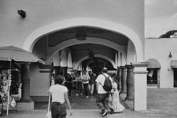 Gente entrando al mercado bajo un arco de cantera