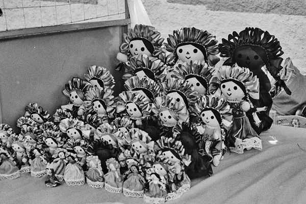 Muñecas artesanales apiladas en un puesto